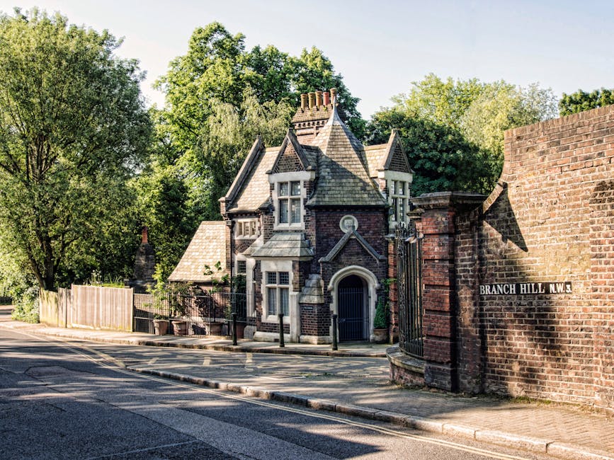 A historic Victorian-style house situated behind a brick entrance wall with an iron gate, located on Branch Hill N.W.3. The house features a steeply pitched slate roof with multiple gables, decorative